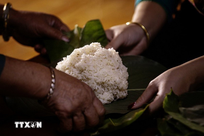 Xôi sau khi chín được quạt nguội rồi gói thành những gói nhỏ vuông vức bằng lá dong. (Ảnh: Trọng Đạt/ TTXVN)