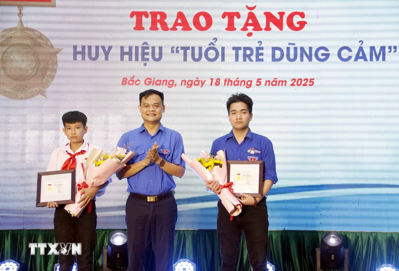 Phó Bí thư Thường trực Tỉnh đoàn Bắc Giang Bùi Văn Hoàng trao tặng Huy hiệu “Tuổi trẻ dũng cảm” cho 2 em là: Phạm Đình Tuấn và Phạm Hoàng Long. (Ảnh: Đồng Thúy/TTXVN)