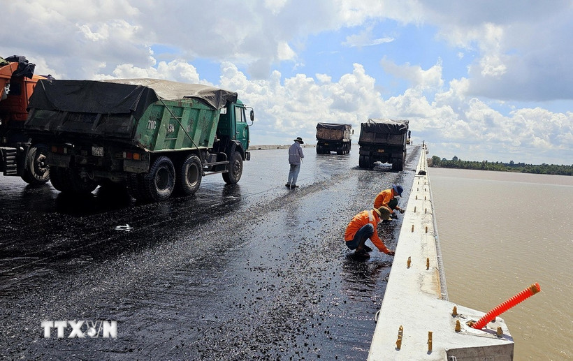 Thi công trải thảm nhựa nóng mặt cầu Đại Ngãi 2, ngày 4/5. (Ảnh: Trung Hiếu/TTXVN)