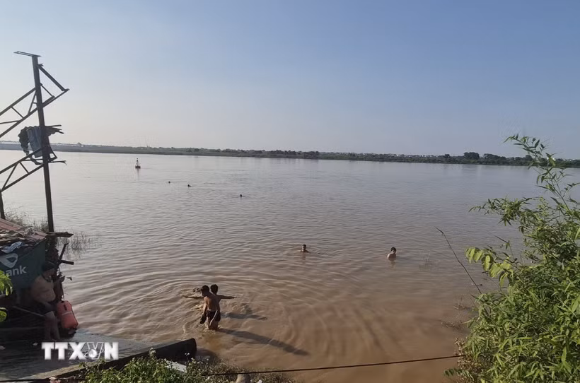 Chỉ vài chục mét sau biển cảnh báo nguy hiểm, nhiều người vẫn vô tư tắm ở bãi tắm tự phát bên bờ sông Hồng, đoạn qua phường Phú Thượng. (Ảnh: Nguyễn Thắng/TTXVN)