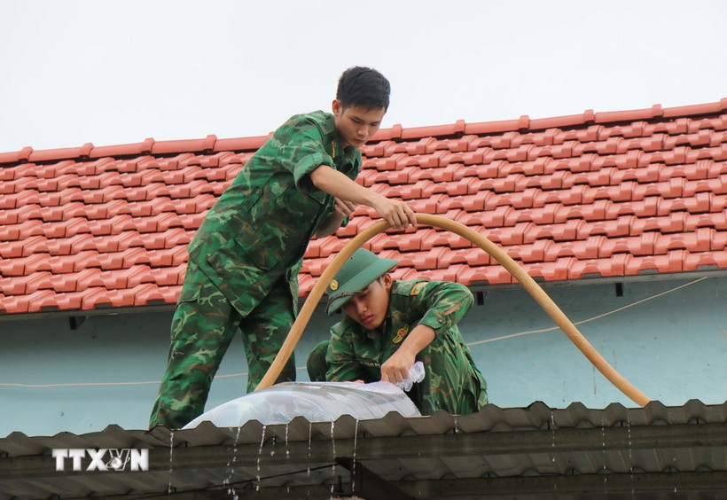 Các cán bộ chiến sỹ Đồn biên phòng Đức Minh giúp người dân xã Mỏ Cày (Quảng Ngãi) gia cố nhà cửa trước bão số 13. (Ảnh: Phạm Cường/TTXVN)