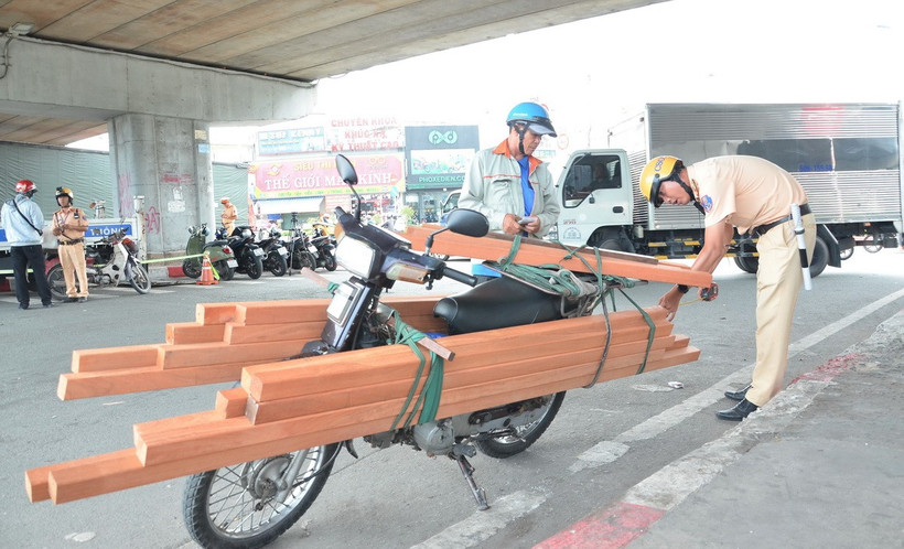 Cảnh sát Giao thông kiểm tra kích thước hàng hóa của một trường hợp vi phạm. (Ảnh: Linh Sơn/TTXVN)