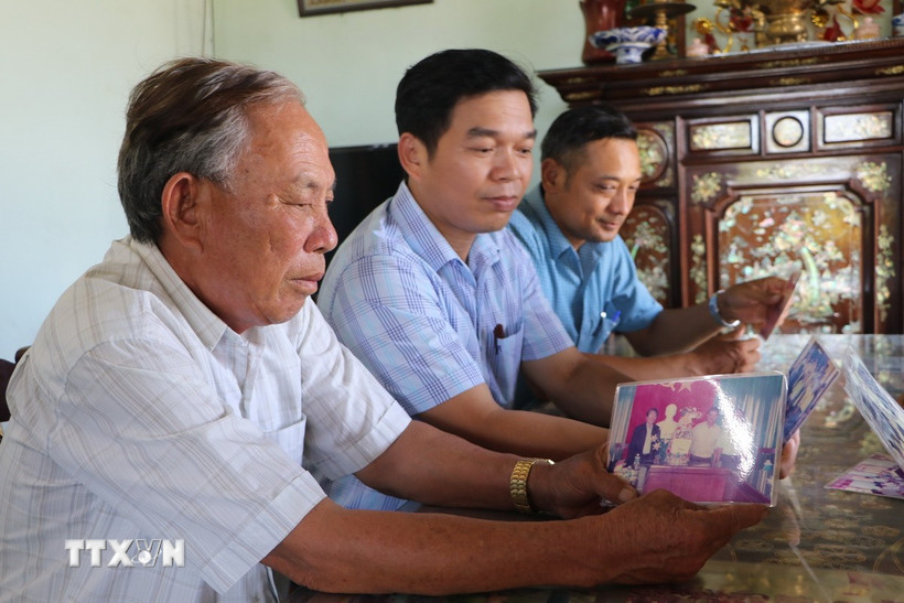 Nguyên Bí thư Đảng ủy xã Phổ Khánh (giai đoạn 2000-2010) Nguyễn Đức Thọ (bìa trái) xem lại tấm ảnh được chụp cùng nguyên Chủ tịch nước Trần Đức Lương. (Ảnh: Đinh Hương/TTXVN)