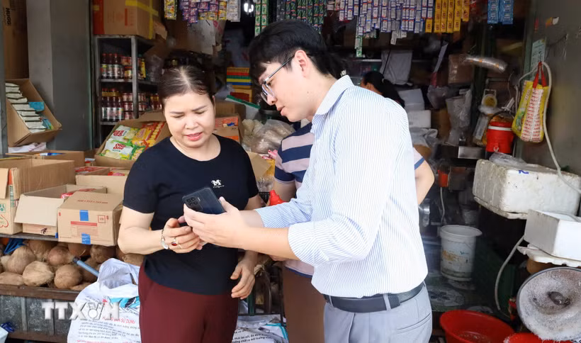 Nhân viên VNPT Đồng Nai hướng dẫn tiểu thương Chợ Đồng Xoài cài đặt, sử dụng các ứng dụng số, từng bước đưa hoạt động kinh doanh lên môi trường số. (Ảnh: Đậu Tất Thành/TTXVN)