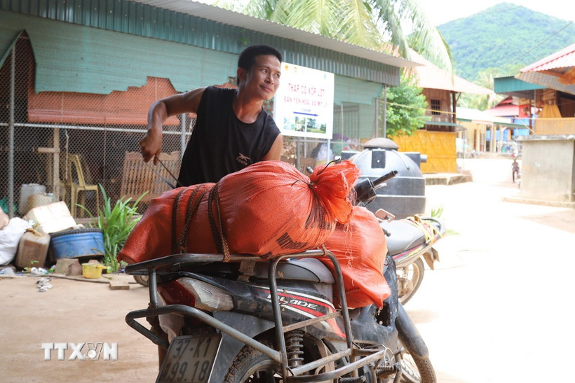 Người dân bản Piêng Pèn (xã Mỹ Lý, tỉnh Nghệ An) ra bản Yên Hòa nhận hàng hỗ trợ được vận chuyển bằng đường sông Nậm Nơn, rồi tiếp tục chở về bản bằng xe máy. (Ảnh: Xuân Tiến/TTXVN)