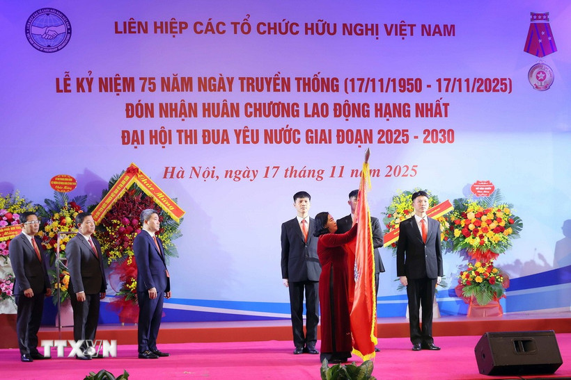 Đồng chí Bùi Thị Minh Hoài, Ủy viên Bộ Chính trị, Bí thư Trung ương Đảng, Bí thư Đảng ủy Mặt trận Tổ quốc, các đoàn thể Trung ương, Chủ tịch Ủy ban Trung ương Mặt trận Tổ quốc Việt Nam gắn Huân chương Lao động hạng Nhất lên lá cờ truyền thống. (Ảnh: An Đăng/ TTXVN)