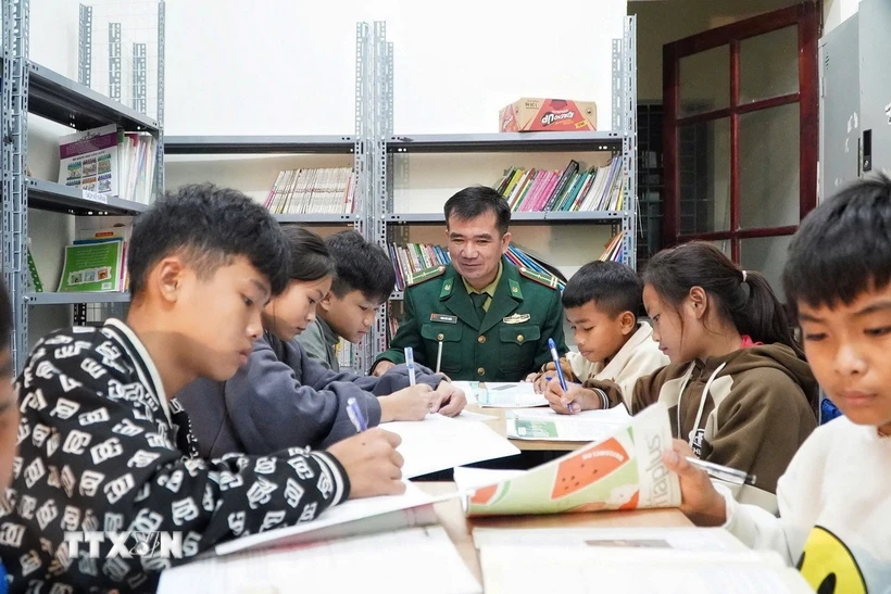 Thiếu tá Nguyễn Văn Thắm, Đồn Biên phòng Môn Sơn hướng dẫn học sinh học tập. (Ảnh: TTXVN phát)