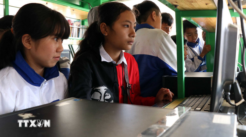 Các em học sinh vùng cao sử dụng máy tính có kết nối internet trên xe thư viện lưu động. (Ảnh: Hữu Quyết/TTXVN)