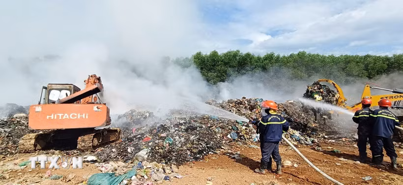 Các lực lượng chức năng đang tập trung nhân lực và phương tiện dập lửa tại Khu xử lý rác Trường Thủy. (Ảnh: TTXVN phát)