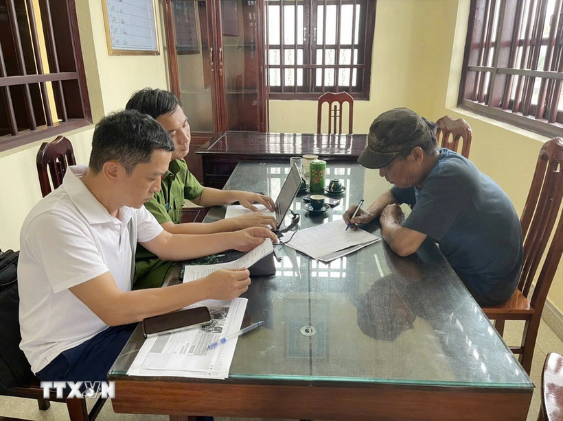 Đối tượng T.V.H (phải) thừa nhận hành vi vi phạm của mình tại cơ quan công an. (Ảnh: TTXVN phát)