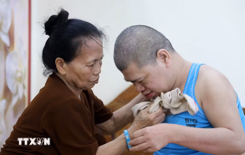 Dù tuổi đã cao nhưng bà Phạm Thị Lán (thôn Thượng Bái xã Diên Hà, tỉnh Hưng Yên) hàng ngày vẫn phải chăm sóc con trai bị ảnh hưởng bởi chất độc da cam/dioxin nằm liệt giường đã 41 năm nay. (Ảnh: Thế Duyệt/TTXVN)
