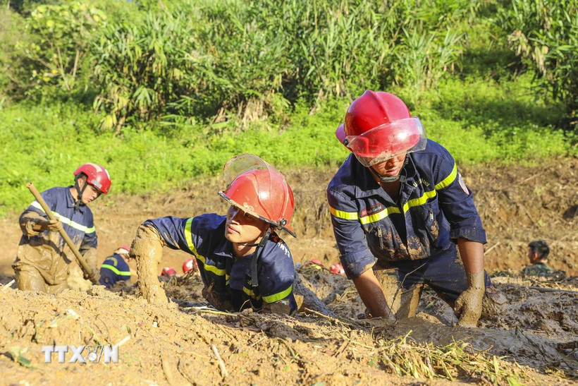 Các chiến sỹ Phòng cháy chữa cháy và Cứu nạn cứu hộ ngâm mình trong bùn đất để tìm kiếm các nạn nhân. (Ảnh: Xuân Tư/TTXVN)