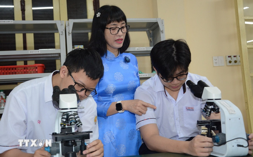 Cô Nguyễn Thị Diệu Hạnh hướng dẫn đội tuyển học sinh giỏi sinh thực hành. (Ảnh: Văn Dũng/TTXVN)