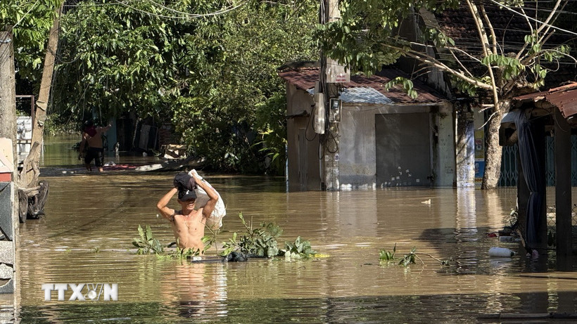 Người dân di chuyển qua vùng ngập lụt. (Ảnh: Tường Quân/TTXVN)