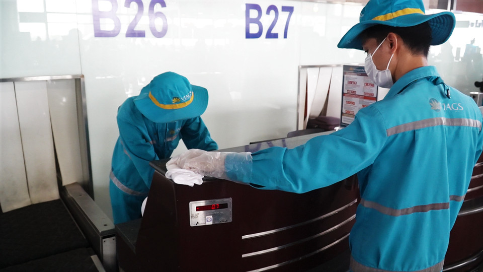 Nhân viên vệ sinh khử khuẩn quầy check-in trước khi đón khách. (Ảnh: PV/Vietnam+)