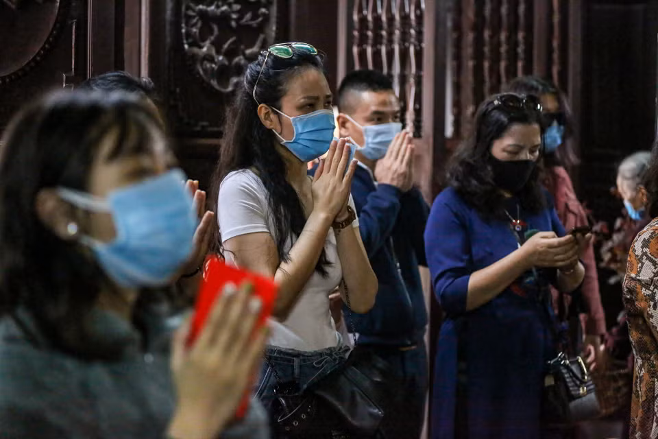 Trong lúc hành lễ, mọi người vẫn phải thực hiện nghiêm quy định đeo khẩu trang trong chùa. (Ảnh: Minh Sơn/Vietnam+)