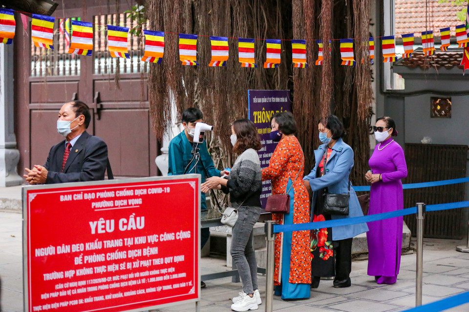 Để được vào chùa, người dân phải thực hiện nghiêm các quy định phòng tránh dịch COVID-19 như đeo khẩu trang, sát khuẩn tay và đo nhiệt độ. (Ảnh: Minh Sơn/Vietnam+)