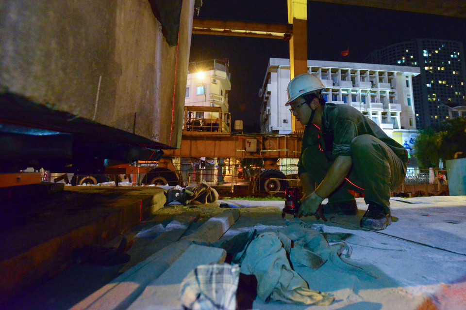 Các kỹ sư phải liên tục dùng thước đo lade để đảm bảo khối bê tông được thăng bằng trước khi kéo lên công trường trên cao. (Ảnh: Minh Sơn/Vietnam+)