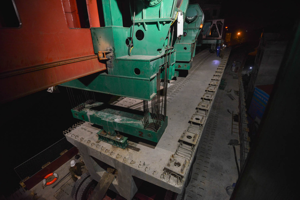 Trước khi nâng lên, các tấm bê tông được cố định 2 đầu và dùng một cẩu trục với 2 đầu kéo siêu trường, siêu trọng nối với 2 trailer thủy lực tại điểm đầu và điểm cuối của các tấm dầm bê tông. (Ảnh: Minh Sơn/Vietnam+)