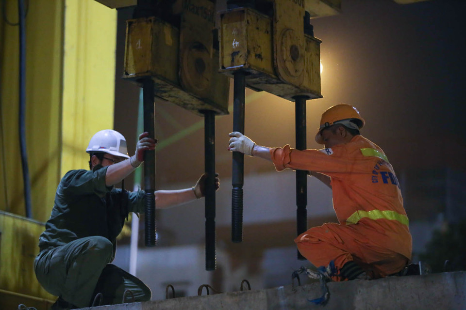 Công nhân đang chuẩn bị công đoạn bắt vít vào tấm bê tông để kéo lên công trình. (Ảnh: Minh Sơn/Vietnam+)