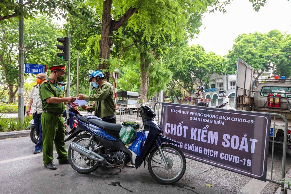 Để qua chốt, người đi đường phải trình giấy tờ nêu lý do chính đáng, do cơ quan, công ty cấp có dấu đỏ. (Ảnh: Minh Sơn/Vietnam+)