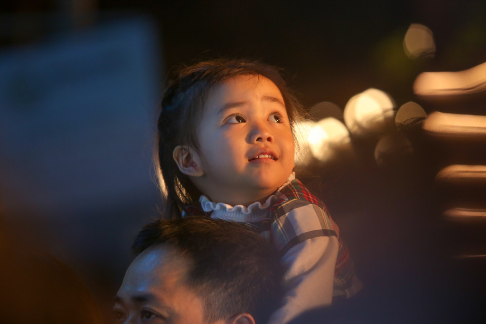 Một bé gái ngước nhìn lên kim đồng hồ đếm ngược chờ đón khoảnh khắc sang năm mới. (Ảnh: PV/Vietnam+)