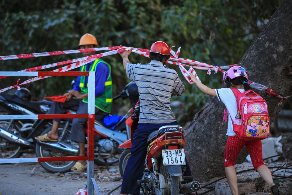 Tuy nhiên có một số người dân vẫn cố tình ‘vượt rào’ để đi trong sự bất lực của công nhân phụ trách. (Ảnh: Minh Sơn/Vietnam+)
