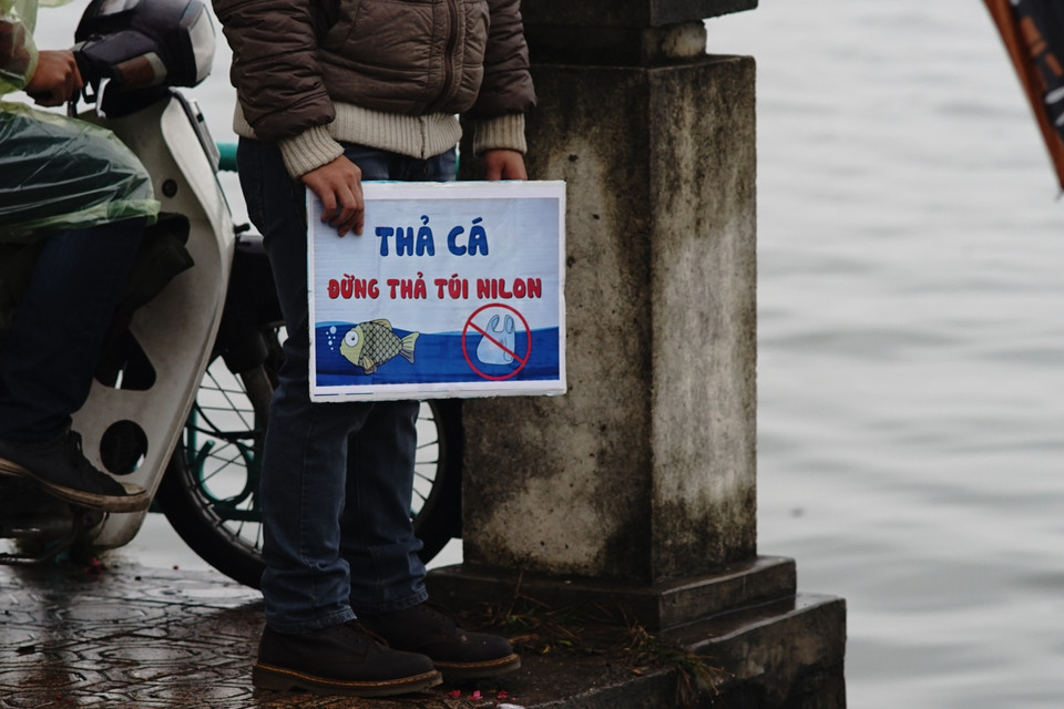  Một nhóm các bạn trẻ mang tấm bảng ghi khẩu hiệu: ‘Thả cá đừng thả túi nilon’ để giúp người dân nâng cao ý thức bảo vệ môi trường. (Ảnh: Thành Nguyễn-Hoàng Long/Vietnam+)