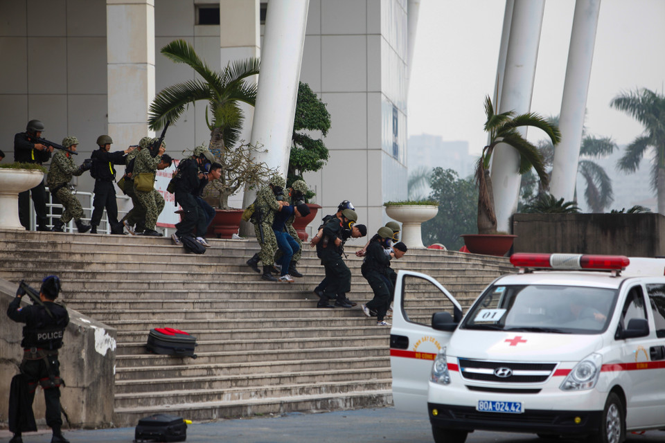 Những nữ cảnh sát đặc nhiệm cùng đồng đội áp giải tội phạm ra xe. (Ảnh: Minh Sơn/Vietnam+)