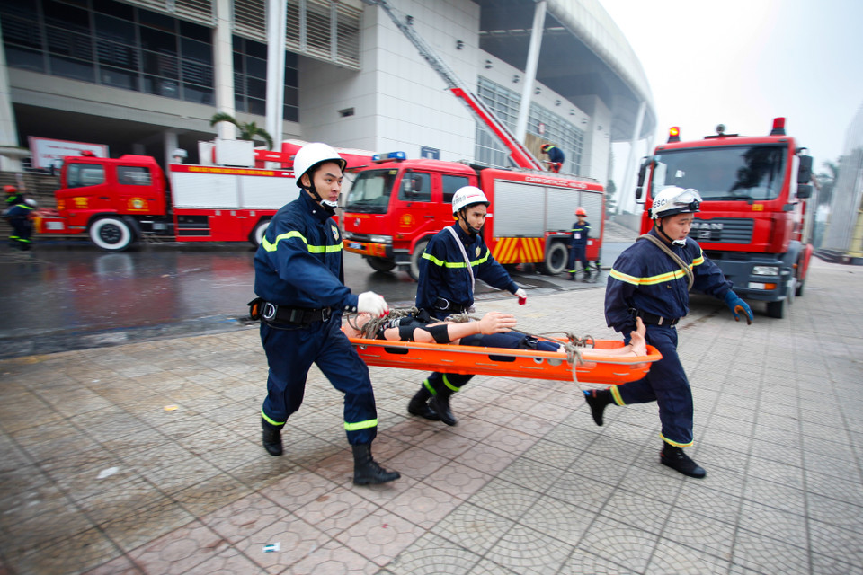 Lực lượng cứu hộ nhanh chóng vận chuyển người bị ngạt khói ra xe cứu thương. (Ảnh: Minh Sơn/Vietnam+)