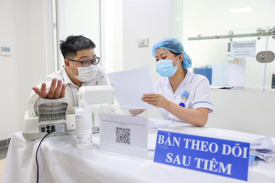 Người đi tiêm phải ở lại điểm tiêm chủng ít nhất 30 phút sau khi tiêm để theo dõi phản ứng và được hướng dẫn tiếp tục theo dõi ở nhà ít nhất 24 giờ sau khi tiêm. (Ảnh: Minh Sơn/Vietnam+)