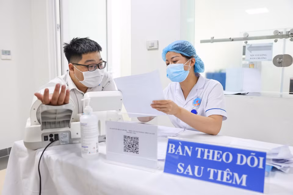 Người đi tiêm phải ở lại điểm tiêm chủng ít nhất 30 phút sau khi tiêm để theo dõi phản ứng và được hướng dẫn tiếp tục theo dõi ở nhà ít nhất 24 giờ sau khi tiêm. (Ảnh: Minh Sơn/Vietnam+)