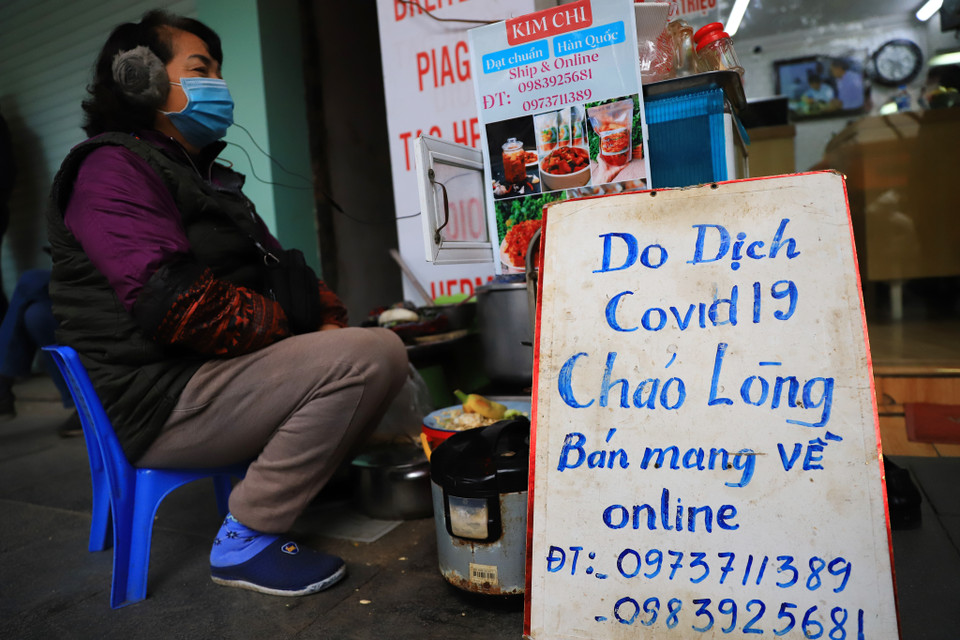 Nhiệt độ thấp cùng với gió tạo nên cái lạnh tê tái, người dân đi làm không chỉ phải mặc các loại áo ấm mà phải quàng thêm khăn, có người phải mặc thêm cả áo mưa để tránh gió lạnh. (Ảnh: Hoài Nam/Vietnam+)