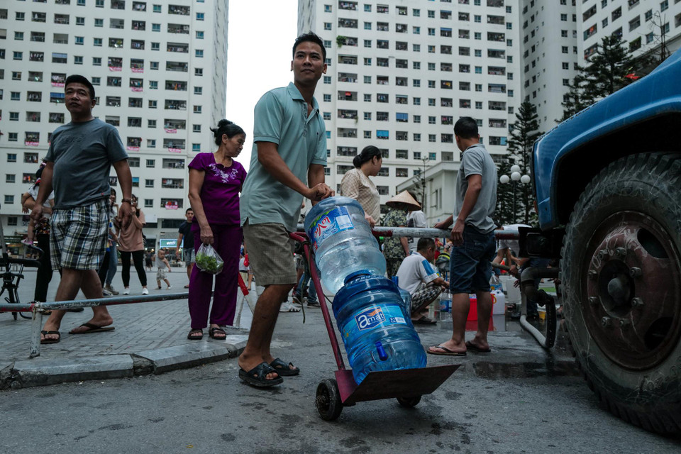 Người mang bình, xô, can… hay bất kì thứ gì có thể đựng được nước. (Ảnh: PV/Vietnam+)
