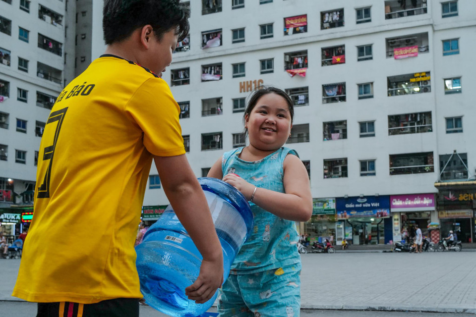 Các em nhỏ phụ giúp gia đình mang nước sạch lên nhà. (Ảnh: PV/Vietnam+)