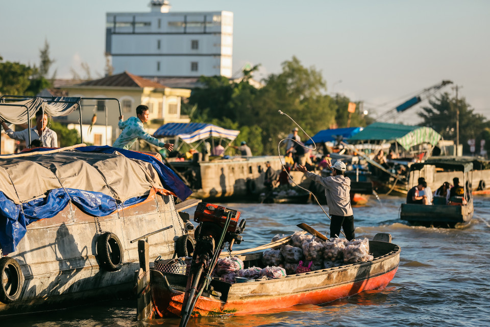 Người dân buôn bán với nhau từ ghe này qua ghe khác bằng cách tung hứng hoặc chuyền tay các món đồ. (Ảnh: Minh Sơn/Vietnam+)