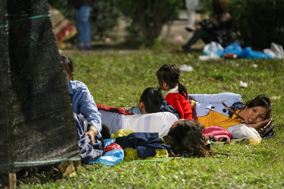 Hàng trăm người dân nằm vật vờ bên các gốc cây, bãi cỏ hoặcchọn cách thuê chiếu, ngả lưng, chờ trời sáng để tránh cảnh chen chúc đi lên Đền Hùng làm lễ. (Ảnh: Minh Sơn/Vietnam+)