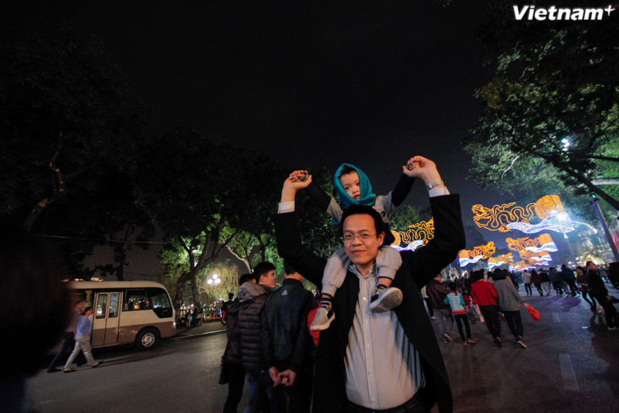 Bố con cõng nhau cùng đi xem pháo hoa. (Ảnh: Thành Nguyễn/Vietnam+)