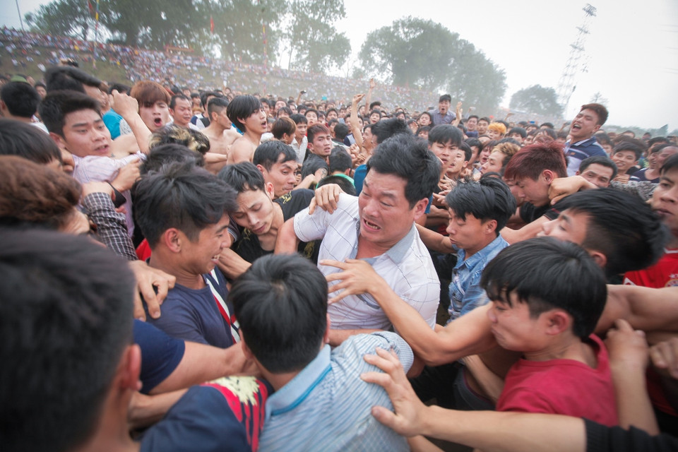 Hàng trăm thanh niên làng lao vào nhau để tranh cướp những quả phết được chôn dưới đất với ý nghĩa ai mang được quả phết này về sẽ được may mắn cả năm. (Ảnh: Thành Nguyễn/Vietnam+)