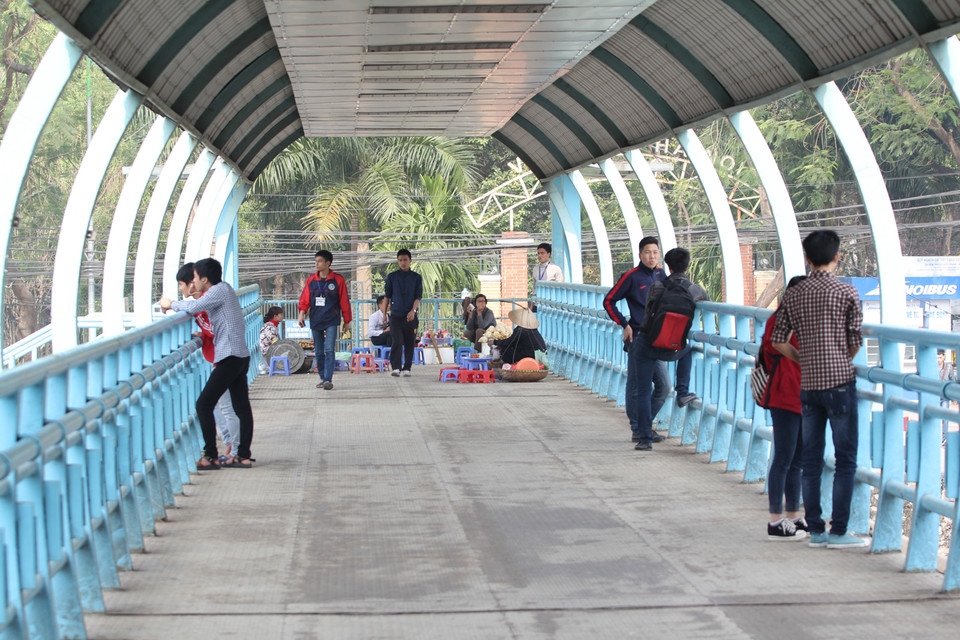 Rất nhiều sinh viên của Đại học Giao thông Vận tải chọn cầu đi bộ làm nơi tụ tập, hẹn hò. Chính vì vậy nhiều hàng quán bất chấp vẫn ngang nhiên chiếm dụng một phần cầu. (Ảnh: Minh Sơn/Vietnam+)