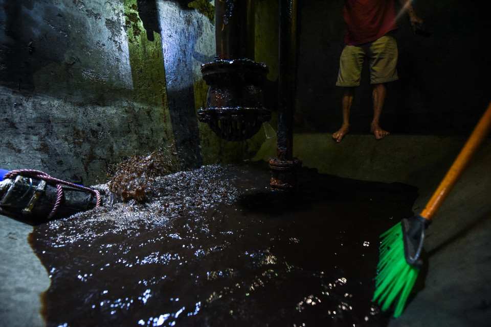 Do nước trong bể đang không đảm bảo, nên công ty buộc phải dùng máy bơm để hút hết nước trong bể ra, sau đó mới tiến hành thau rửa bể. (Ảnh: PV/Vietnam+)