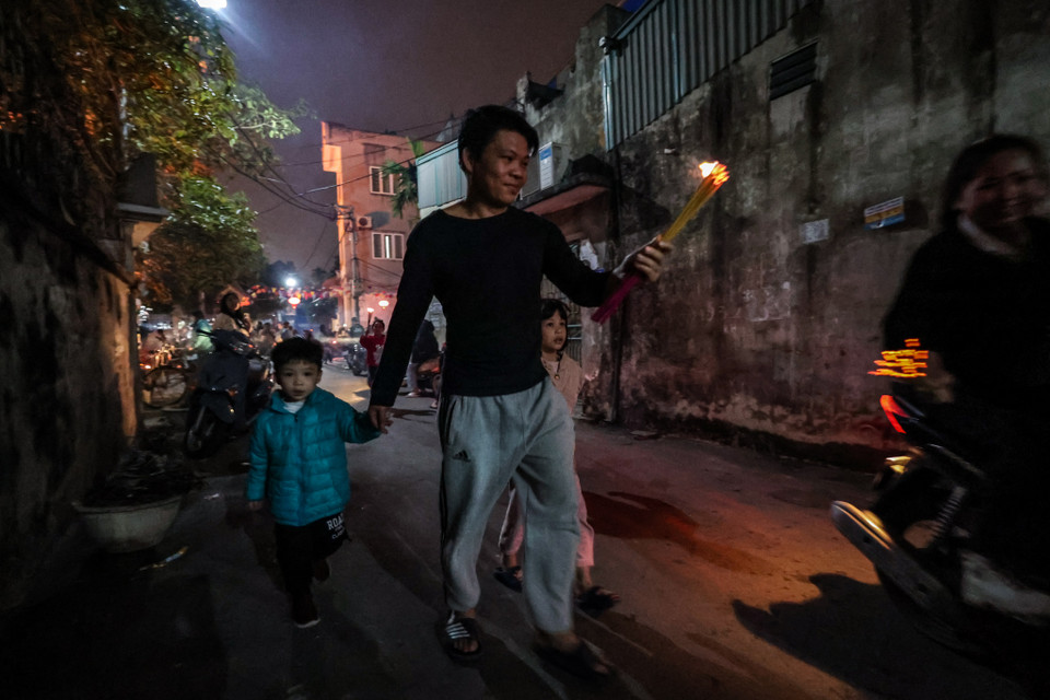 Anh Nguyễn Văn Thắng, một người dân làng An Định cùng 2 con của mình có mặt từ sớm tại đình làng để chờ 'xin đỏ'. (Ảnh: Minh Sơn/Vietnam+)