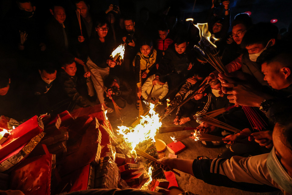 Sau khi cụ đốt hương, vàng mã bằng cây gậy dài, tất cả người tham dự cùng đổ xô vào châm lửa. (Ảnh: Minh Sơn/Vietnam+)