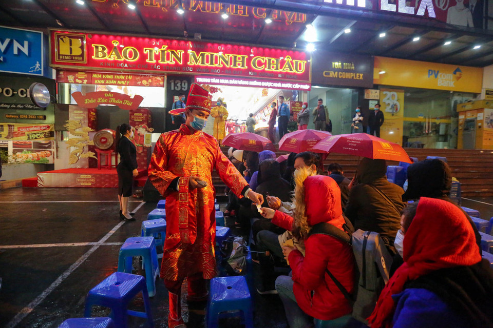 Mặc dù trời mưa nhưng vẫn không ngăn được cảnh người dân xếp hàng mua vàng cầu mong một năm mới may mắn. (Ảnh: Minh Sơn/Vietnam+)