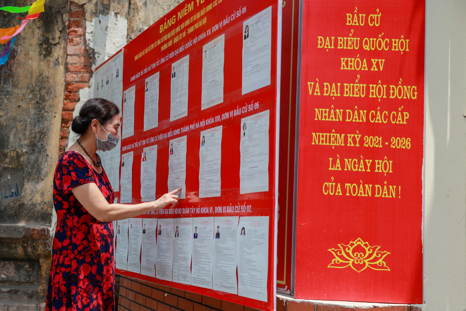 Cử tri đang theo dõi danh sách người ứng cử đại biểu Quốc hội khóa XV và đại biểu Hội đồng nhân dân các cấp nhiệm kỳ 2021-2026 trên bảng niêm yết danh sách người ứng cử. (Ảnh: Minh Sơn/Vietnam+) 