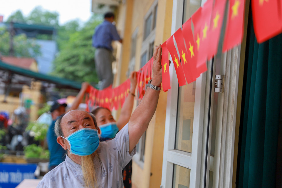 Cán bộ tại khu vực phường Mễ Trì, quận Nam Từ Liêm chỉnh trang lại cờ Tổ quốc sẵn sàng cho ngày hội của toàn dân. (Ảnh: Hoài Nam/Vietnam+)