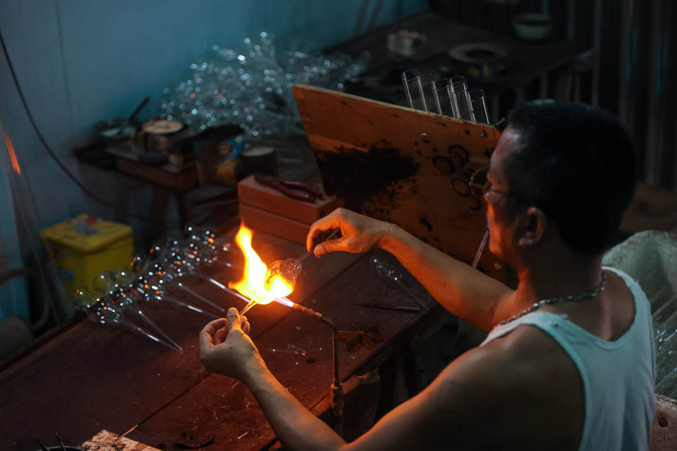 Anh Hồ Quang Hiển, một người thợ làm nghề thổi thủy tinh hơn 34 năm tại làng, cho biết gia đình anh không chỉ làm các sản phẩm đơn giản mà còn làm những vật dụng yêu cầu kỹ thuật cao hơn, cầu kỳ và khéo léo hơn. (Ảnh: Minh Sơn/Vietnam+)