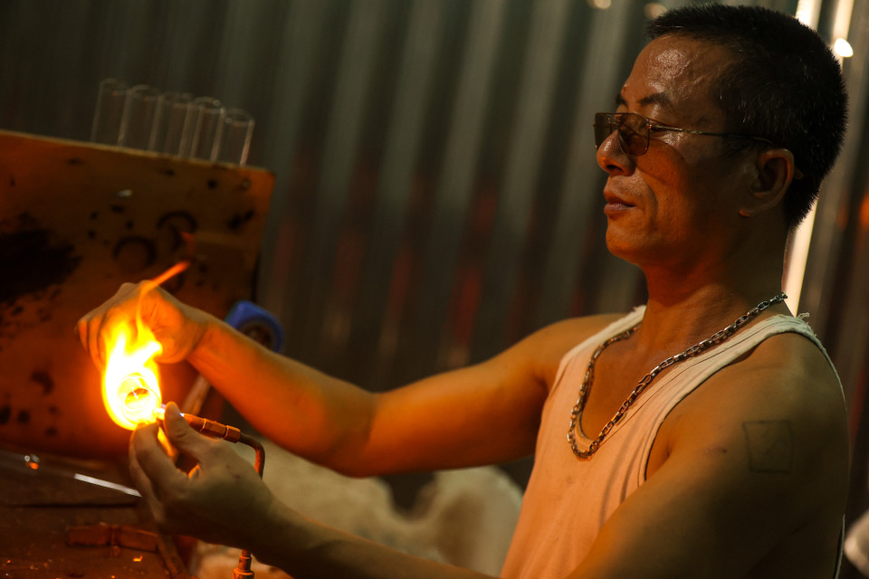 Để cho ra những sản phẩm ưng ý và đẹp mắt, anh Hiển phải làm việc trong điều kiện khắc nghiệt bên cạnh một ngọn lửa khò với nhiệt lượng rất lớn khoảng hơn 700 độ C, có nhiều loại thủy tinh nhiệt độ phải lên đến hơn 1.000 độ C. (Ảnh: Minh Sơn/Vietnam+)