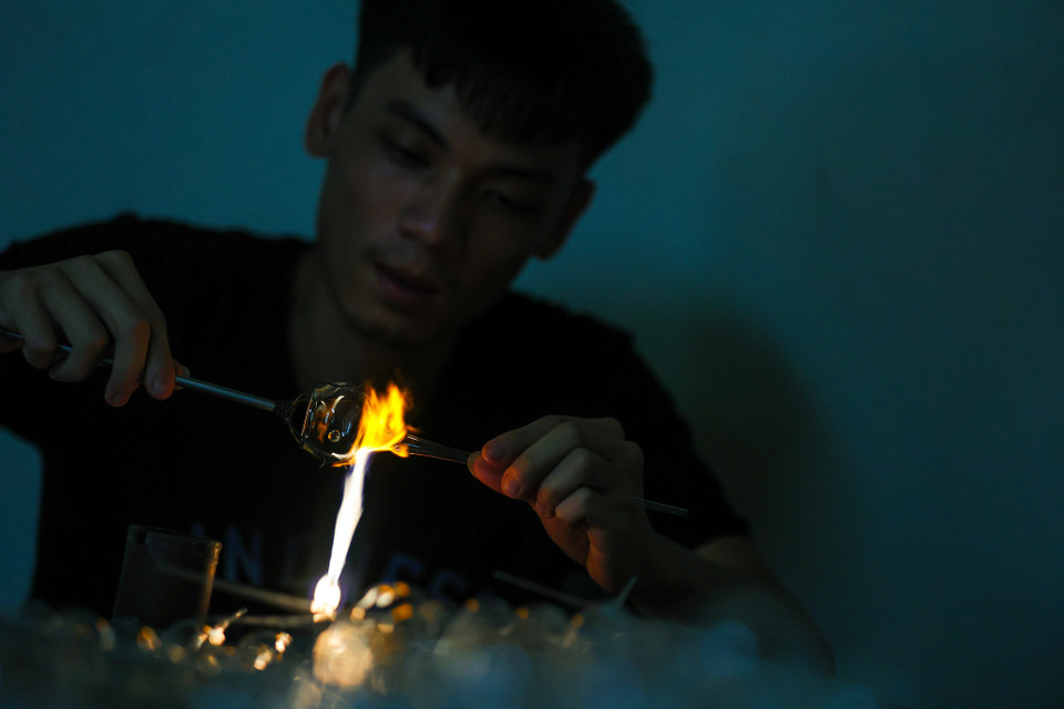 Ông Lê Xuân Tiến, chủ xưởng cho hay: 'Nghề làm thủy tinh do ông bà, bố mẹ tôi truyền lại, rồi đến đời tôi tiếp nối giữ gìn đã hơn 30 năm. Phải yêu nghề và chịu được gian khổ vì suốt ngày làm việc với nhiệt độ cao, lợi nhuận cũng không được tốt.' (Ảnh: Minh Sơn/Vietnam+)