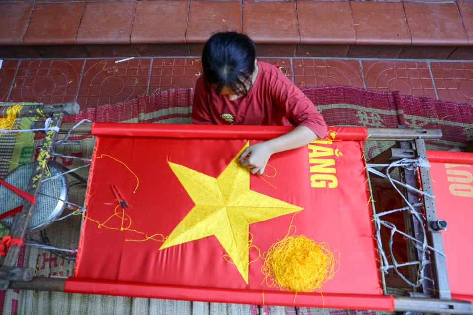 Cũng theo chị Nhung, tiền thuê nhân công thêu cờ bằng tay cũng cao hơn so với nhân công may cờ, từ 200.000 - 250.000 đồng/người/ngày. (Ảnh: Minh Sơn/Vietnam+)